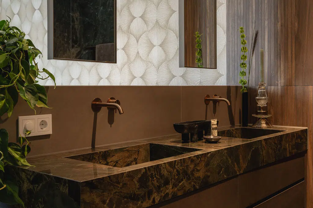 Impressie van een design wastafel, voorzien van een marmer blad in de kleur groen. De wastafel heeft Gessi kranen in de kleur warm bronze.