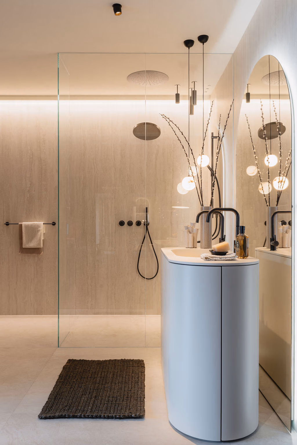 Impressie van een design badkamer, ingericht met travertin tegels in een warme kleur, kitkat tegels, kranen in geborsteld gunmetal en een maatwerk kast.