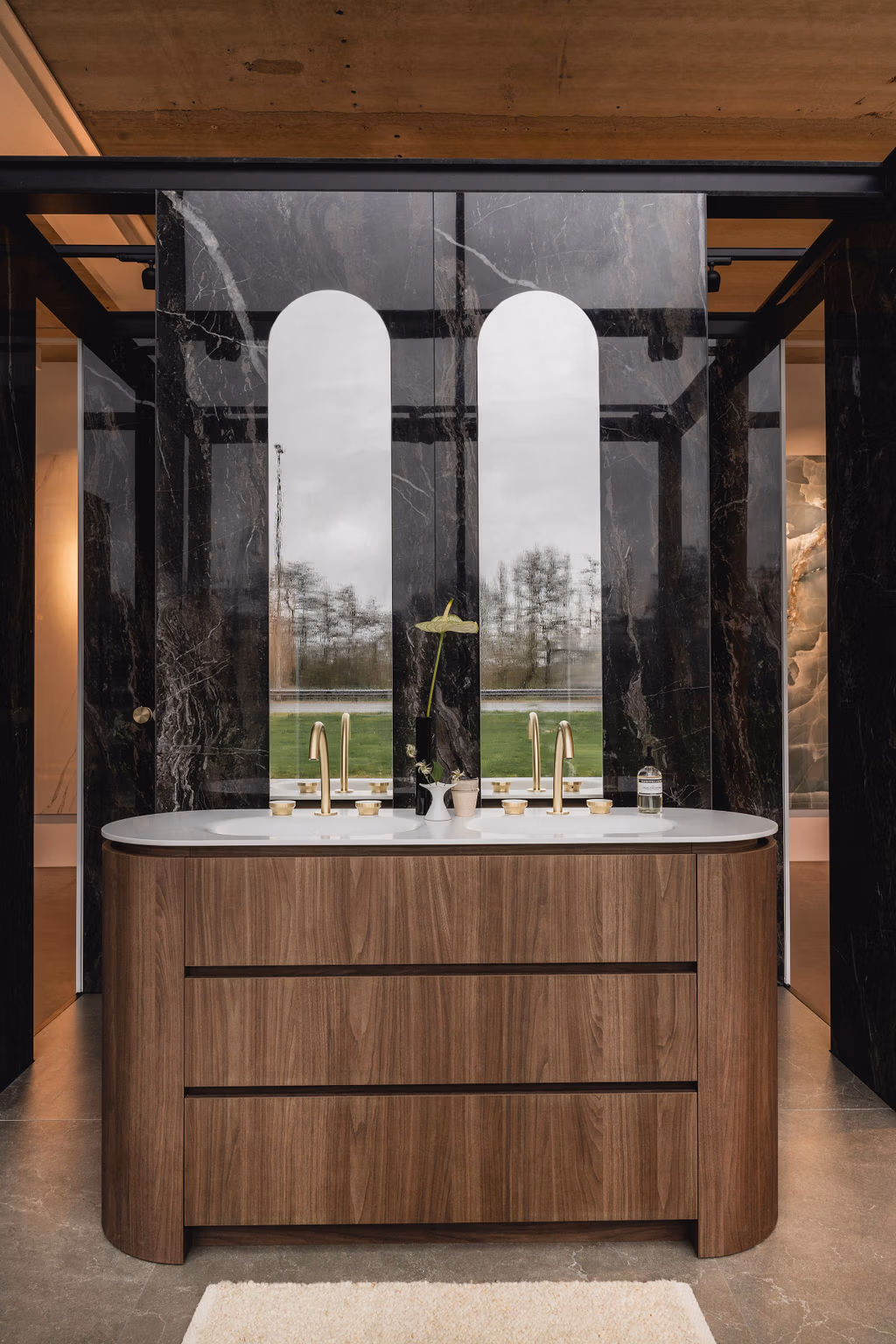 Impressie van de showroom van De Eerste Kamer Badkamers, waar we een luxe badkamer met maatwerk houten wastafel zien, voorzien van Gessi kranen.
